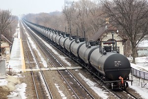 Effective in April 2015, a DOT emergency order requires that trains containing 20 or more loaded tank cars in a continuous block, or 35 or more loaded tank cars of Class 3 flammable liquid, and&#x2F;or at least one DOT Specification 111 (DOT-111) tank car, must not exceed a maximum speed of 40 mph in High Threat Urban Areas. This eastbound BNSF oil train, at Highlands Metra station in Hinsdale, Ill., on Feb. 21, 2015, would have been affected. Photo by David Lassen.